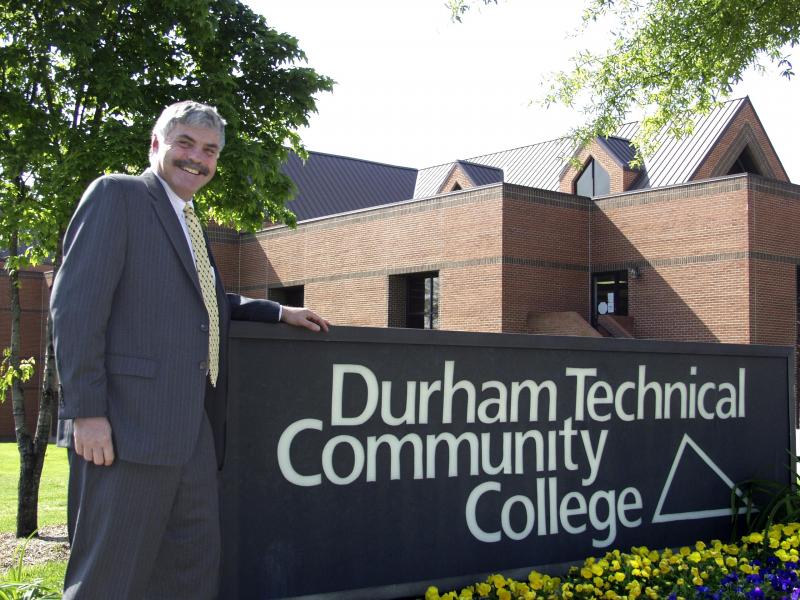 dr. ingram standing next to a large sign that says durham technical community college