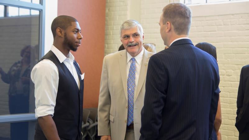 Dr. ingram speaks to two students at an event 
