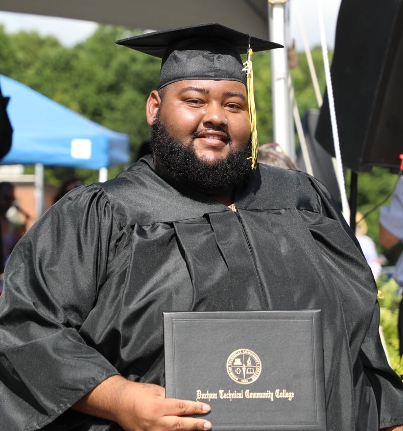 man holding degree after walking across stage