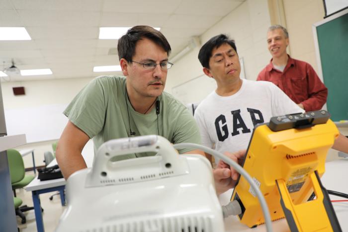 two people overlooking equipment on a table