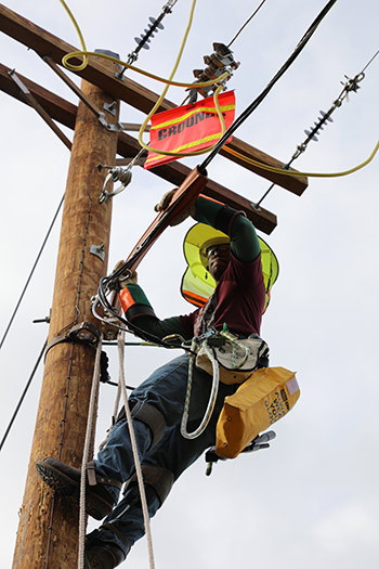Electric Line Technician student at the top of a power line pole