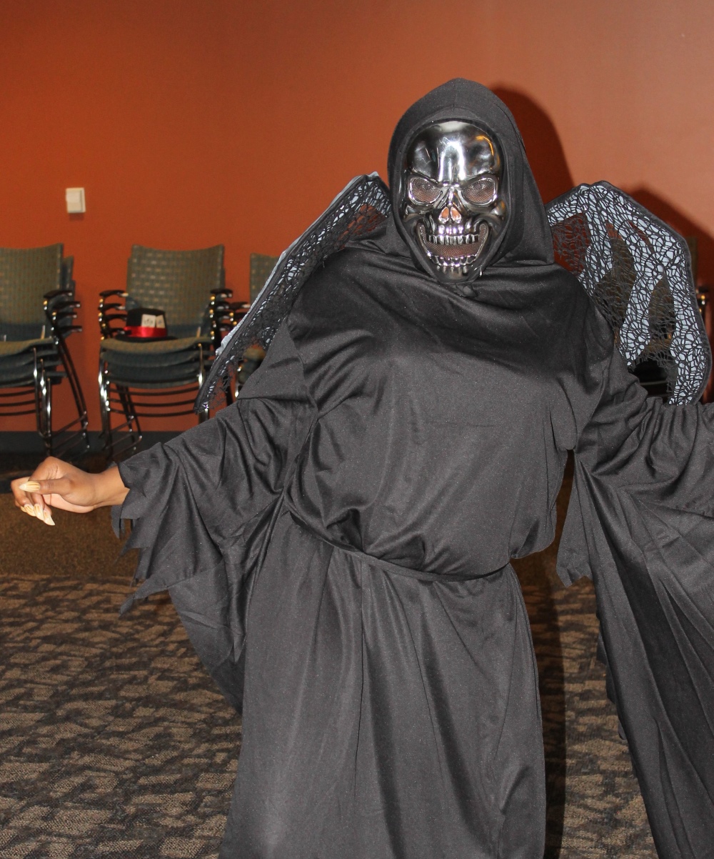 Durham Tech student dancing and having a good time wearing a halloween costume cosisting of a black cloak and a chrome skull mask