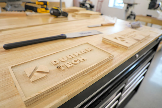 woodworking lab with tools and a finished sign that reads Durham Tech