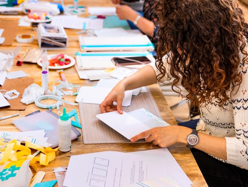 A woman folding colored paper to make a zine