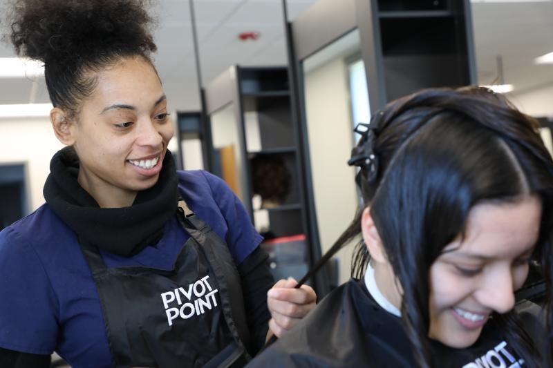 student standing behind another student cutting her hair