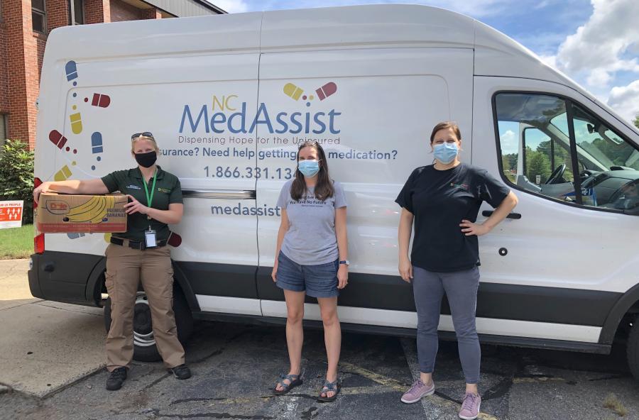 three people standing in front of a MedAssist van with masks