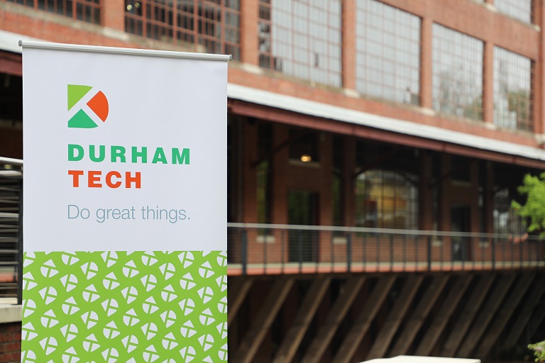 sign of durham tech logo in front of brick building