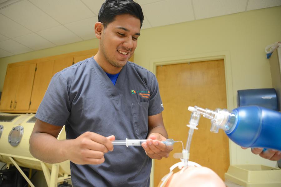 student standing behind a mannequin's head practicing intubation