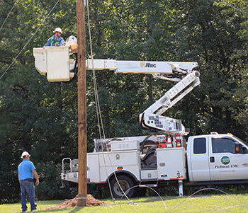 electrical line worker being lifted in bucket of a truck to fix wiring on phone pole