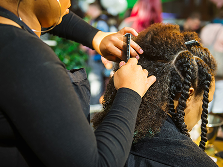 Hair stylist braiding another woman's hair