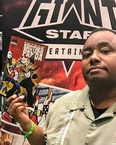 Eric McRay holds up a colorful comic book titled Brother Panda