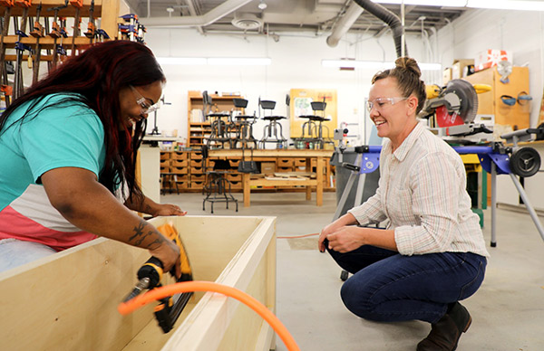 student using nail gun while the instructor supervises