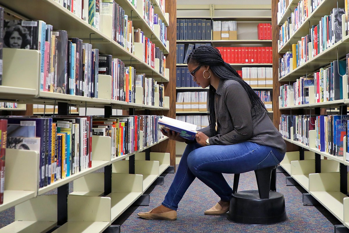 student looking through a book in a library