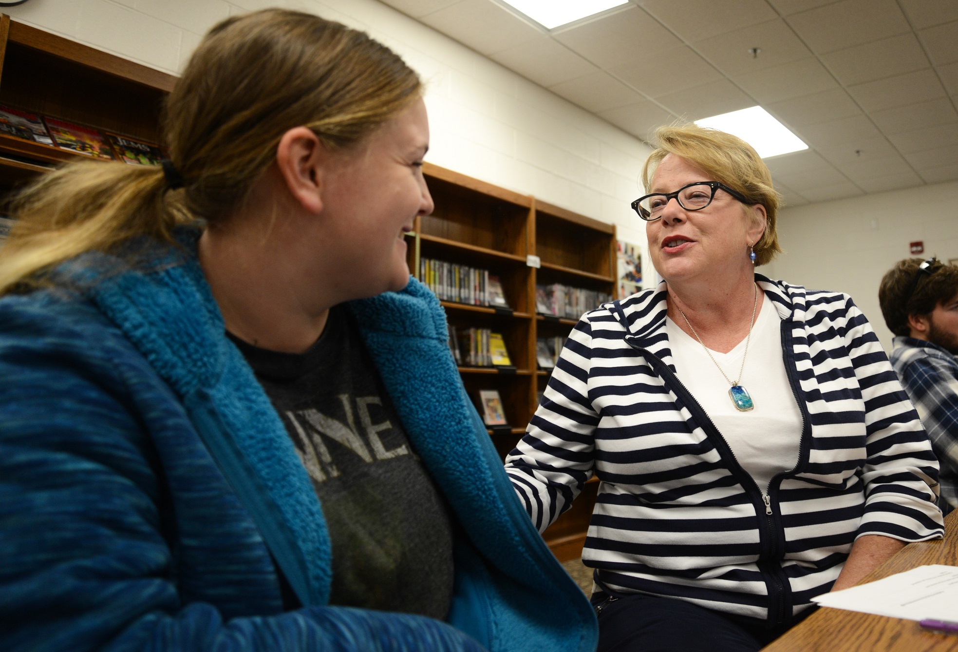 student smiling at Mary Moore while sitting in library on Orange County Campus