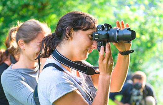 students using professional looking cameras to photograph something offscreen 