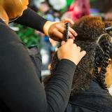 Hair stylist braiding another woman's hair