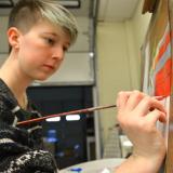 A student in the Associate in Fine Arts program at Durham Tech paints with her right hand.